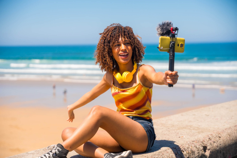 Influencer creating content on beach with smartphone gimbal